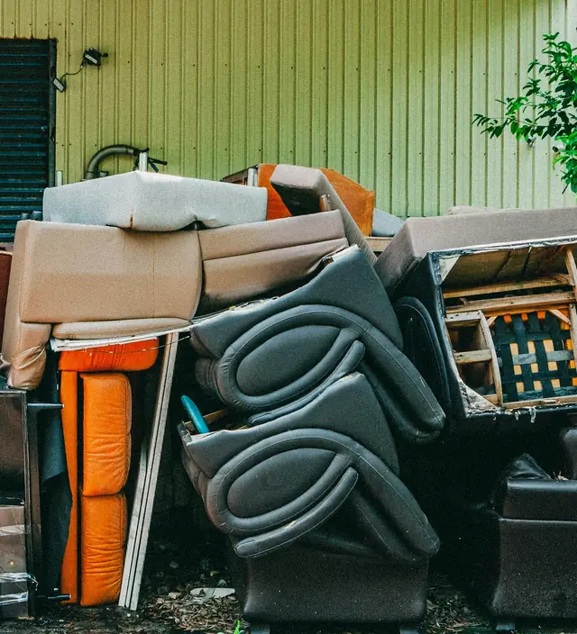 Pile of old couches and chairs waiting for junk removal outside an Atlanta garage
